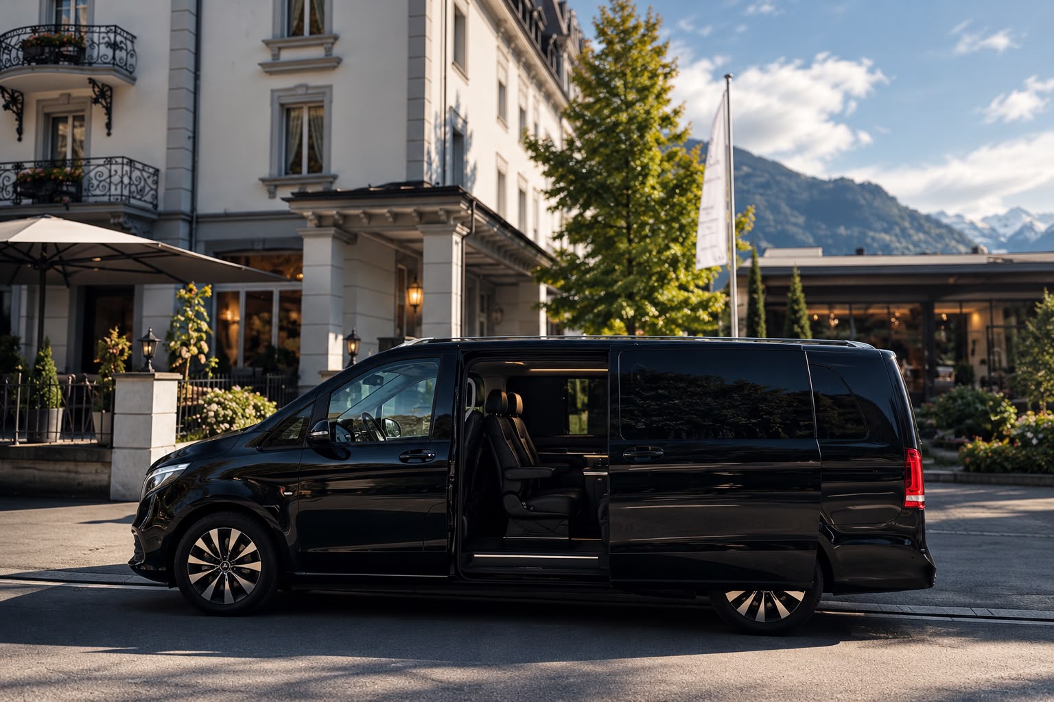 Schwarzer Premium-Van vor einem Hotel mit Bergkulisse